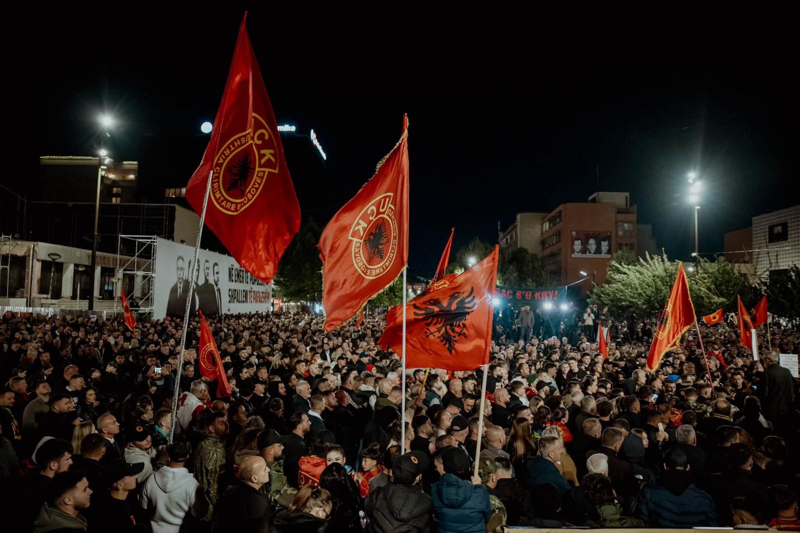A night-time crowd in Prishtina with KLA and Albanian flags