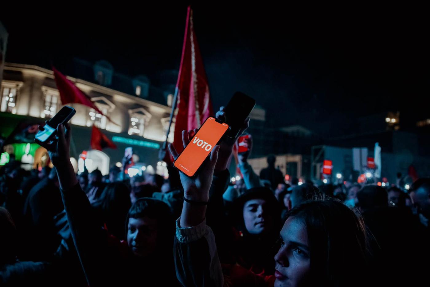 A raised phone showing the word VOTO in a protest crowd